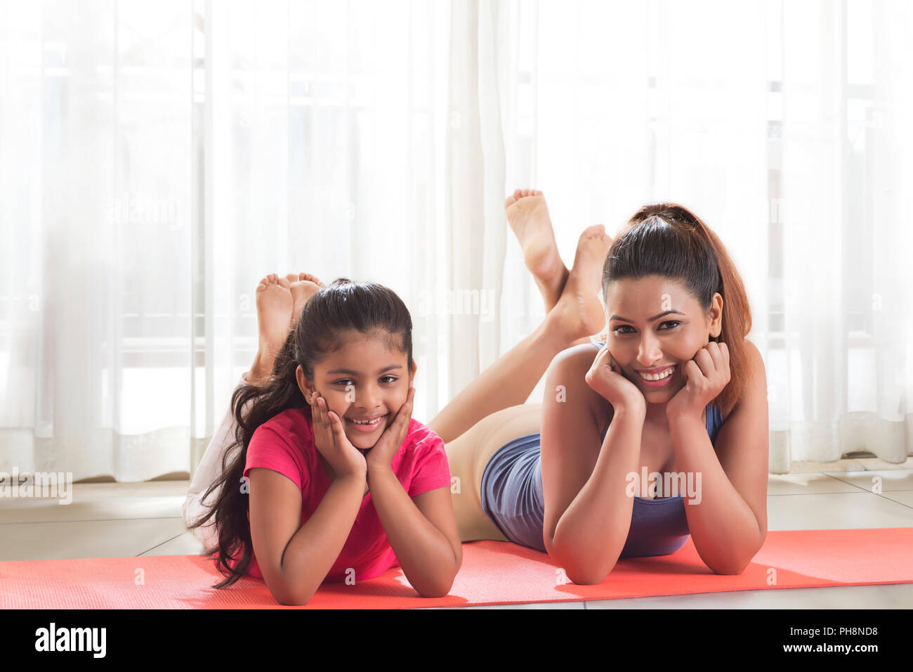 Happy mother and daughter lying on yoga mat Banque D'Images