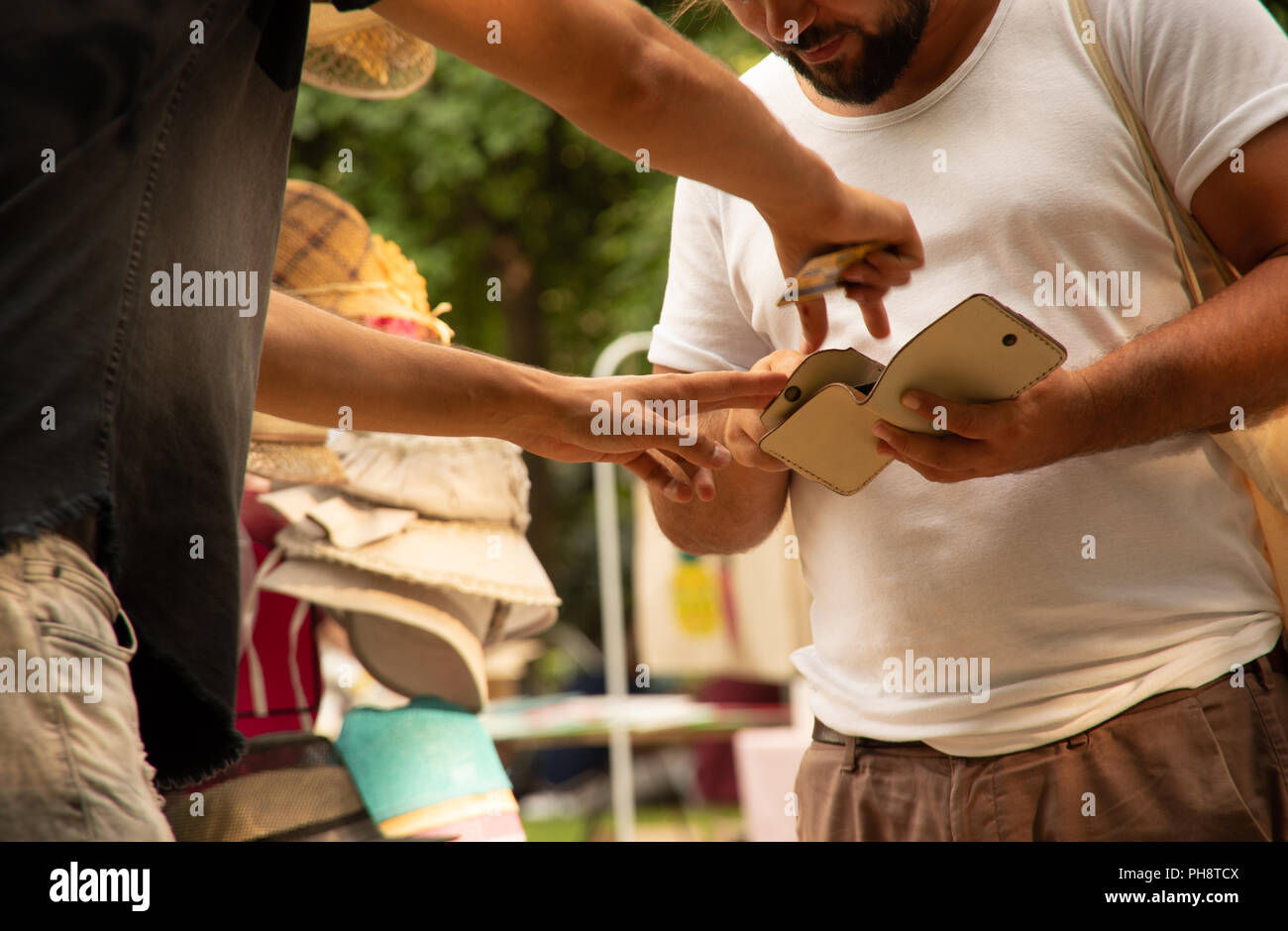 Vendeur montrant les caractéristiques de la clientèle en portefeuille cuir outdoor market stall Banque D'Images