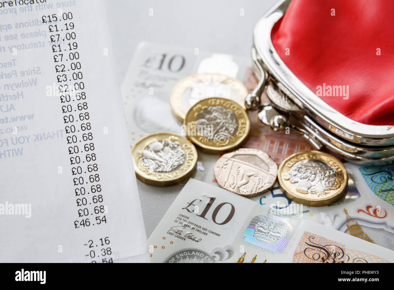 Supermarché shopping jusqu'à réception avec de l'argent Sterling pièces et billets de livre et un sac rouge d'argent. Angleterre, Royaume-Uni, Grande-Bretagne Banque D'Images