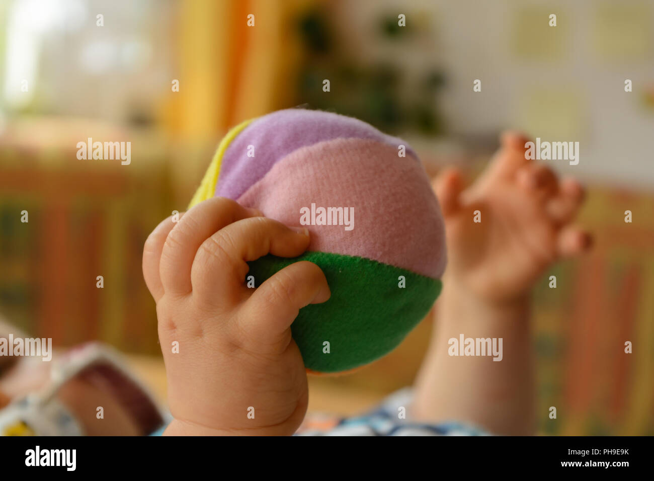 Les mains de bébé jouant avec une balle molle - close up Banque D'Images