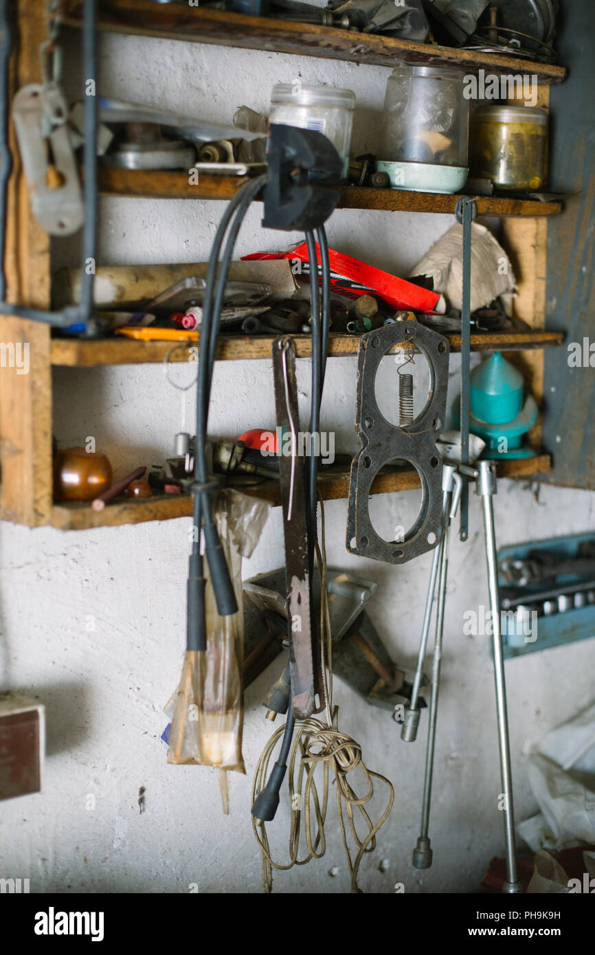 Plateau en désordre dans le garage avec de vieux outils, câbles et pièces de voiture Banque D'Images