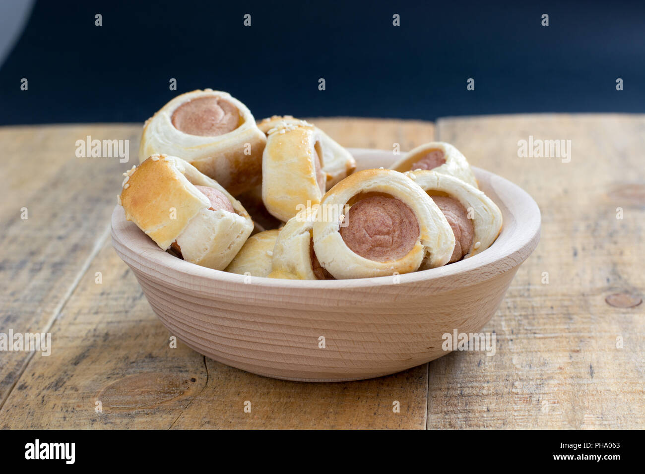 Saucisses roulées dans un croissant au four pâte sur rack de refroidissement du métal. Banque D'Images