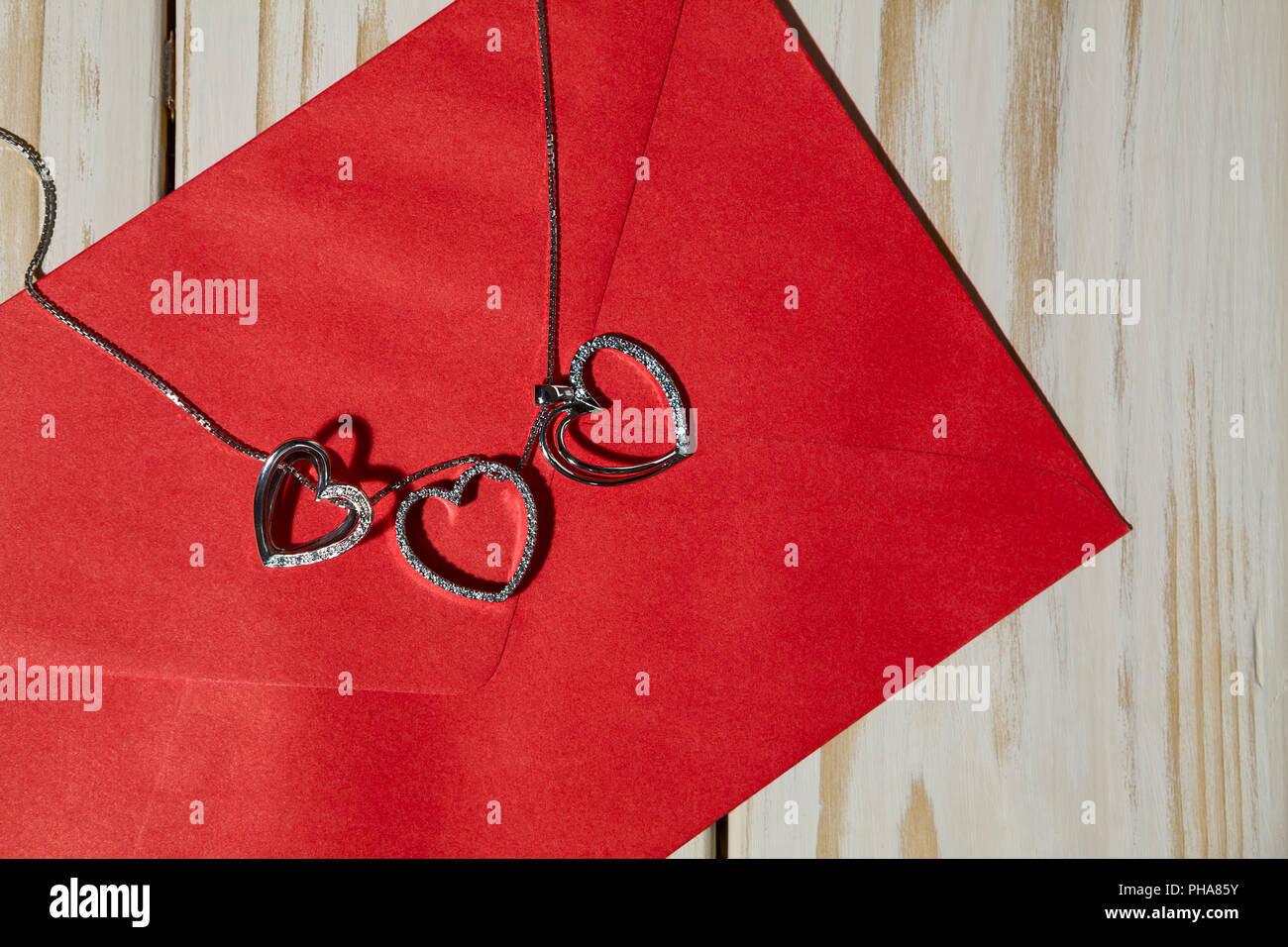 Libre d'argent pendentifs coeur sur une enveloppe rouge Banque D'Images