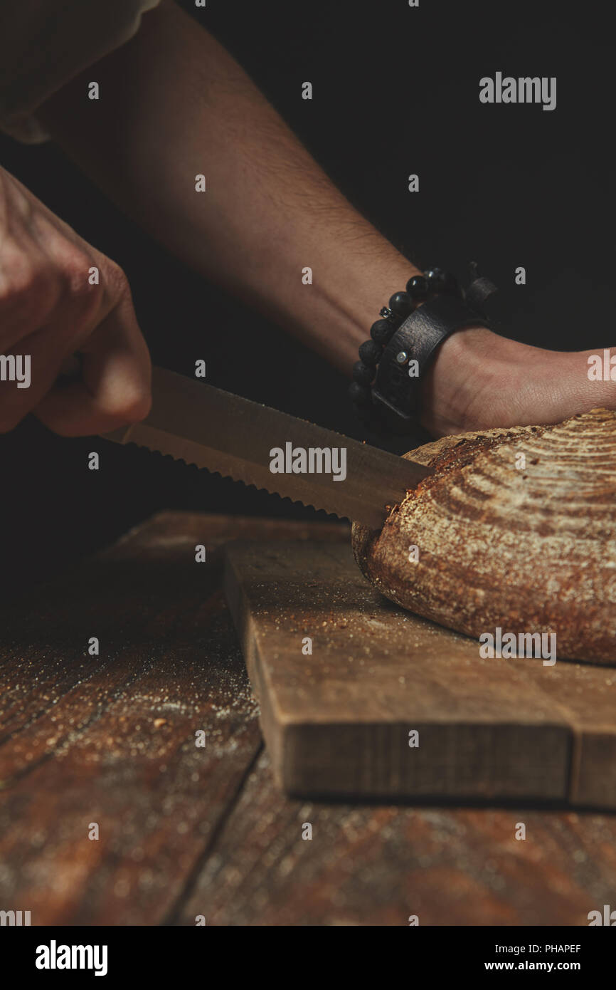 Man slicing délicieux pain frais. Banque D'Images