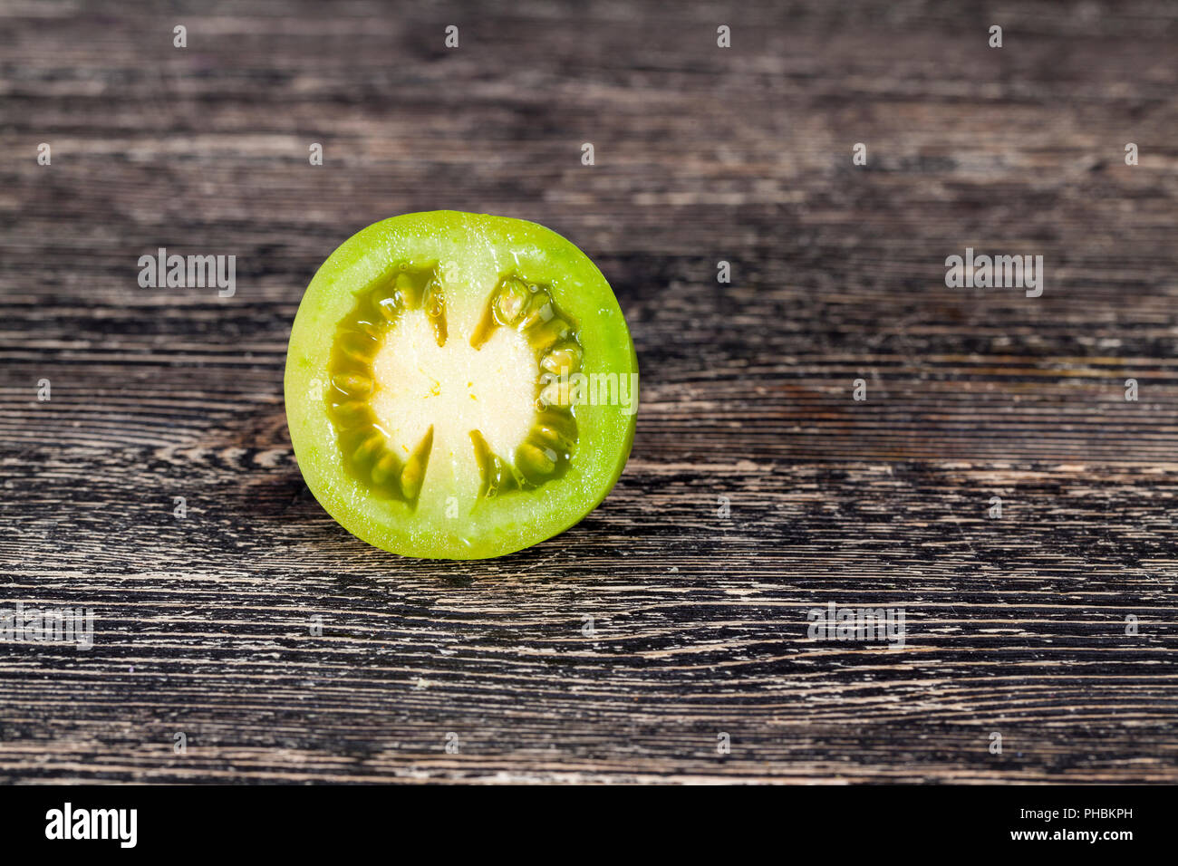 La moitié d'une coupe de tomate verte sur un tableau noir, gros plan Banque D'Images
