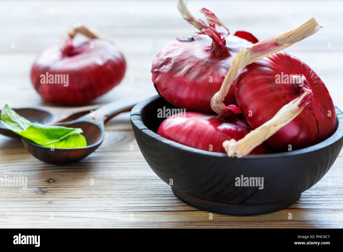 Oignons rouges doux dans un bol en bois noir. Banque D'Images