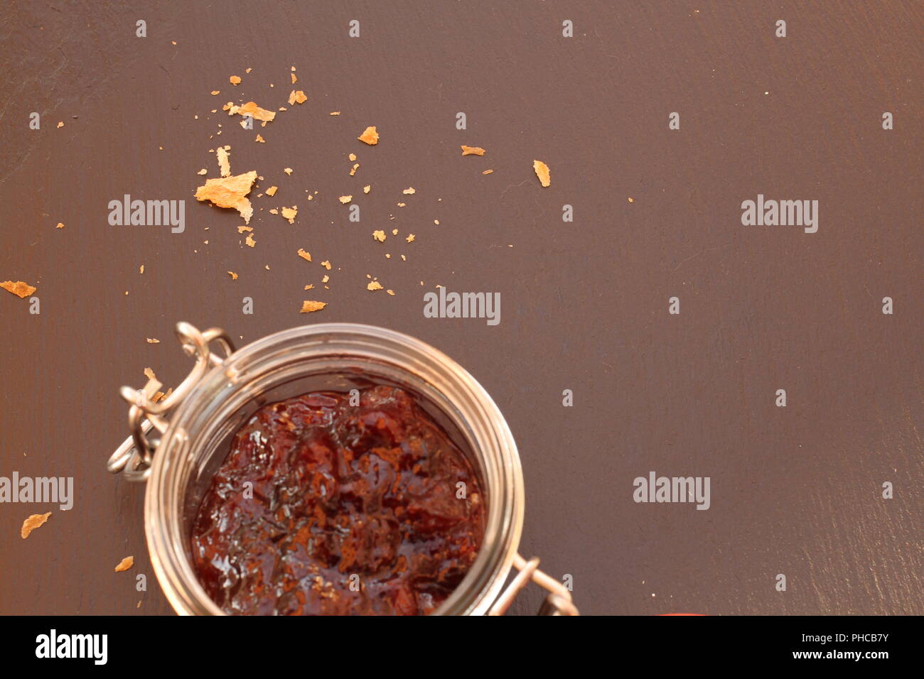 Pot de confiture en verre avec des miettes sur fond noir Banque D'Images