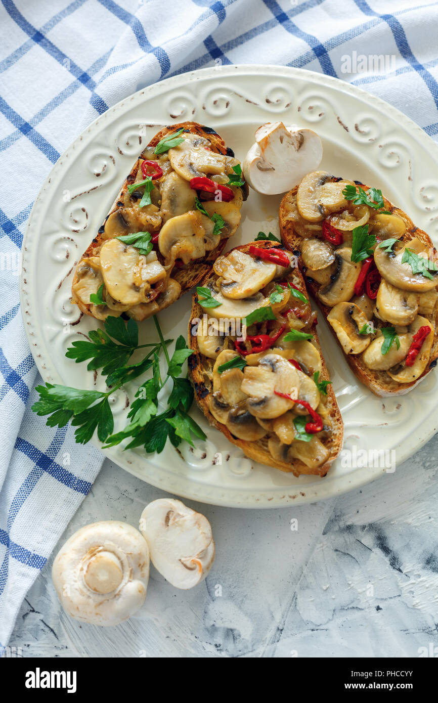 Crostini avec champignons et oignons sur une assiette blanche. Banque D'Images