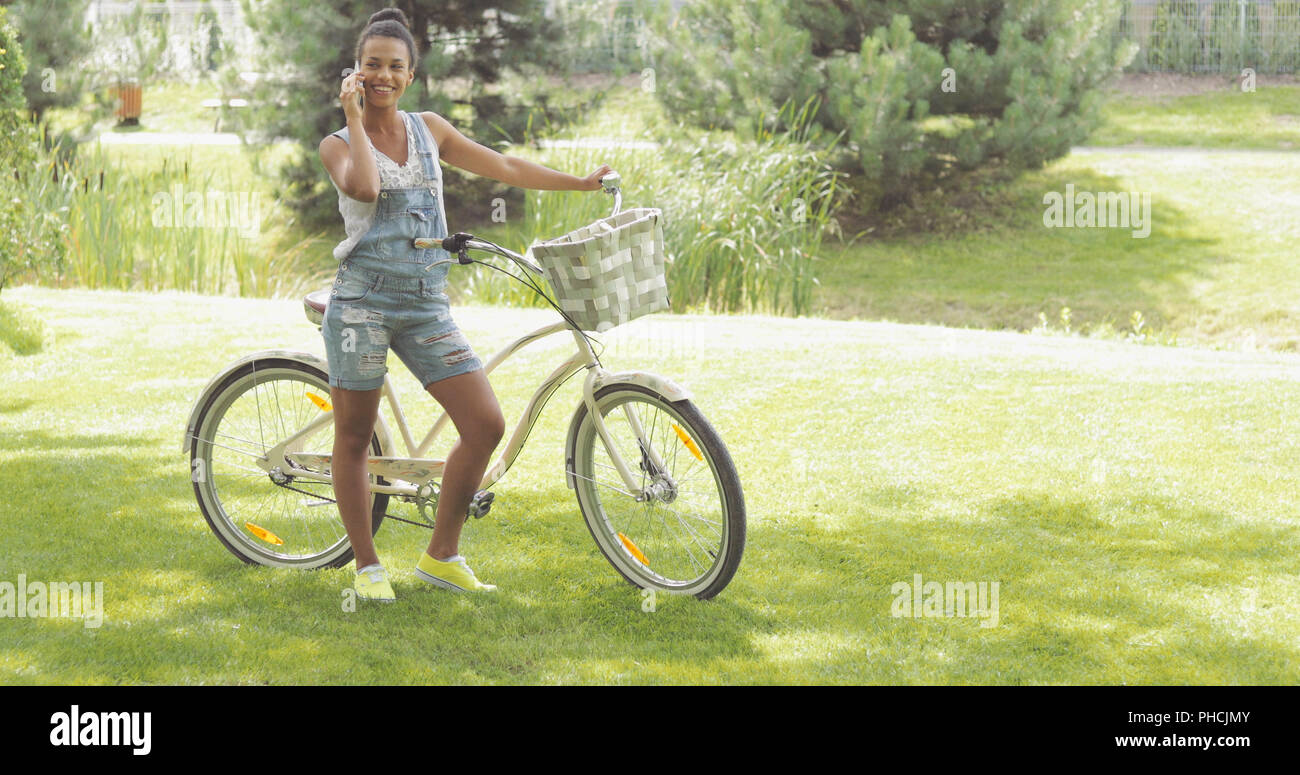 Parler jeune cycliste phone in park Banque D'Images
