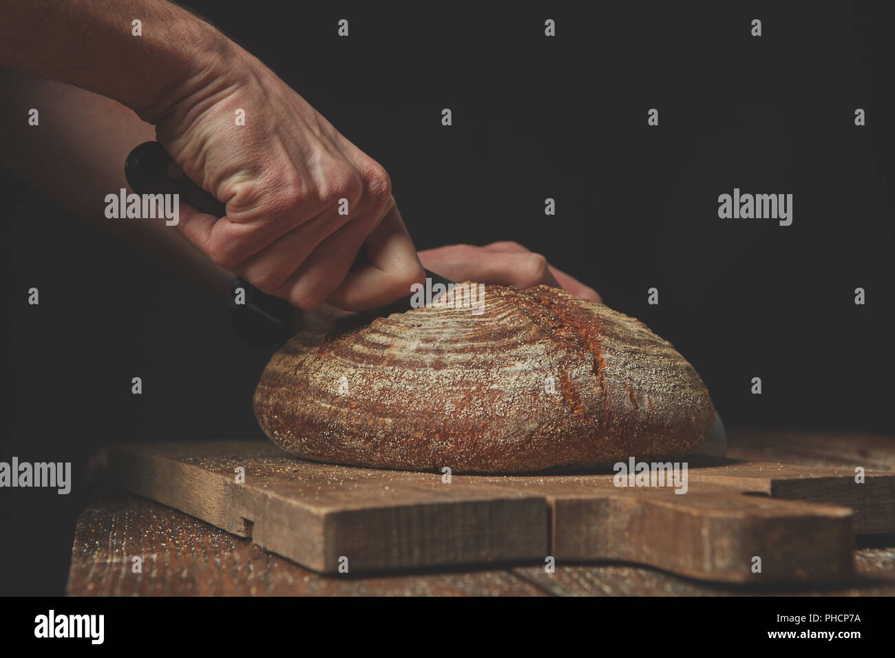Man slicing délicieux pain frais. Banque D'Images