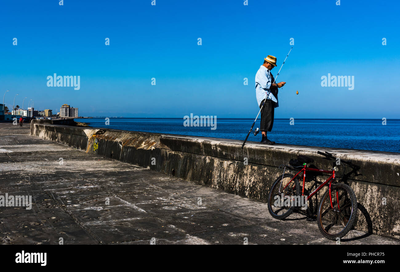 Homme cubain preps canne à pêche avant d'un après-midi de pêche sur le Malecon à La Havane, Cuba. Banque D'Images