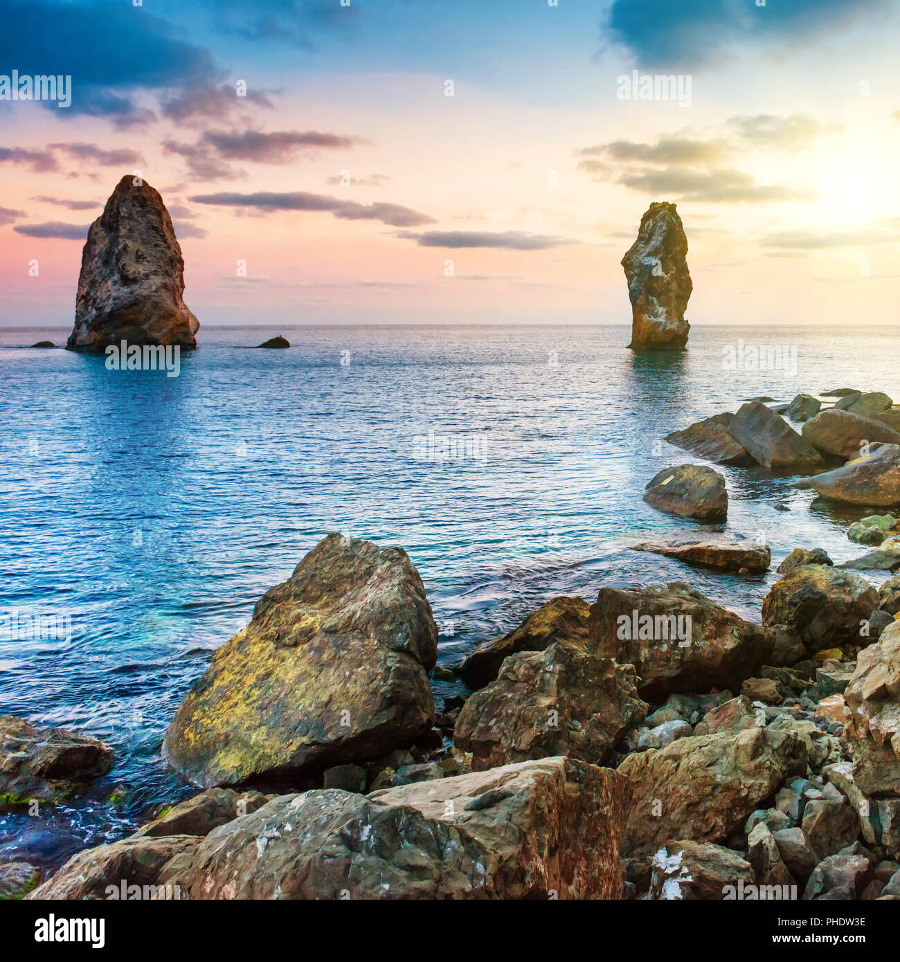 Coucher du soleil sur la mer au-dessus de gros rochers Banque D'Images