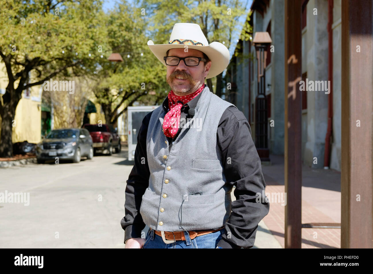 Un cowboy texan avec un foulard au cou rouge et blanc chapeau de cowboy cowboy et vêtements, se trouve à l'extérieur de Fort Worth Stockyards, Texas. L'horizontale. Banque D'Images
