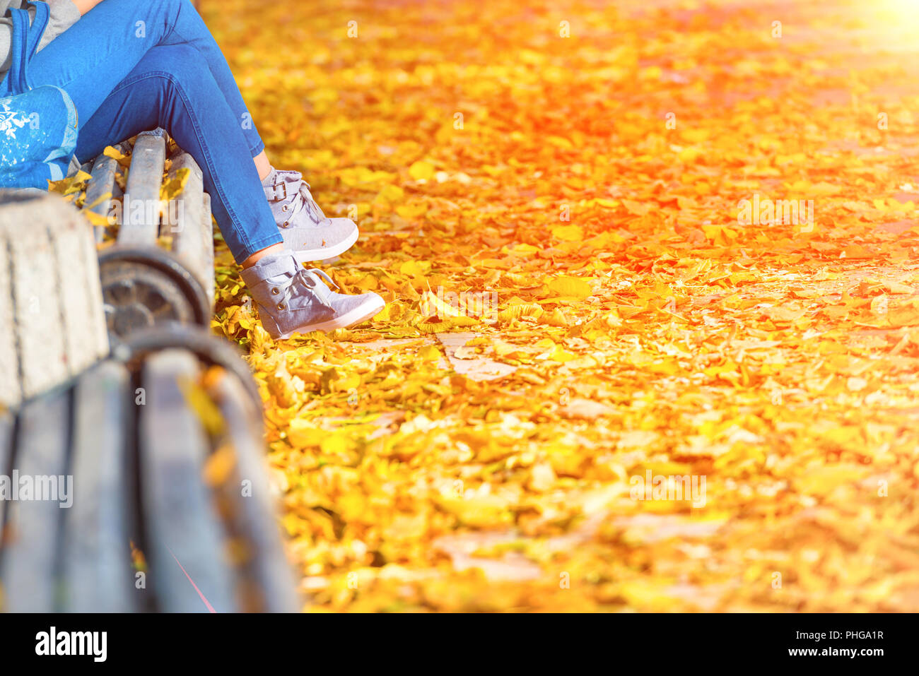 Jeune femme assise sur un banc dans le parc Banque D'Images