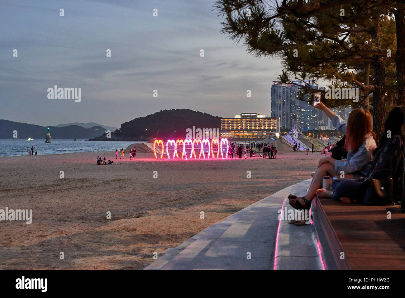 Festival 2018 Sable de Haeundae, Busan, Corée. Girl en tenant assis selfies à sur la plage et la baie au crépuscule. Banque D'Images