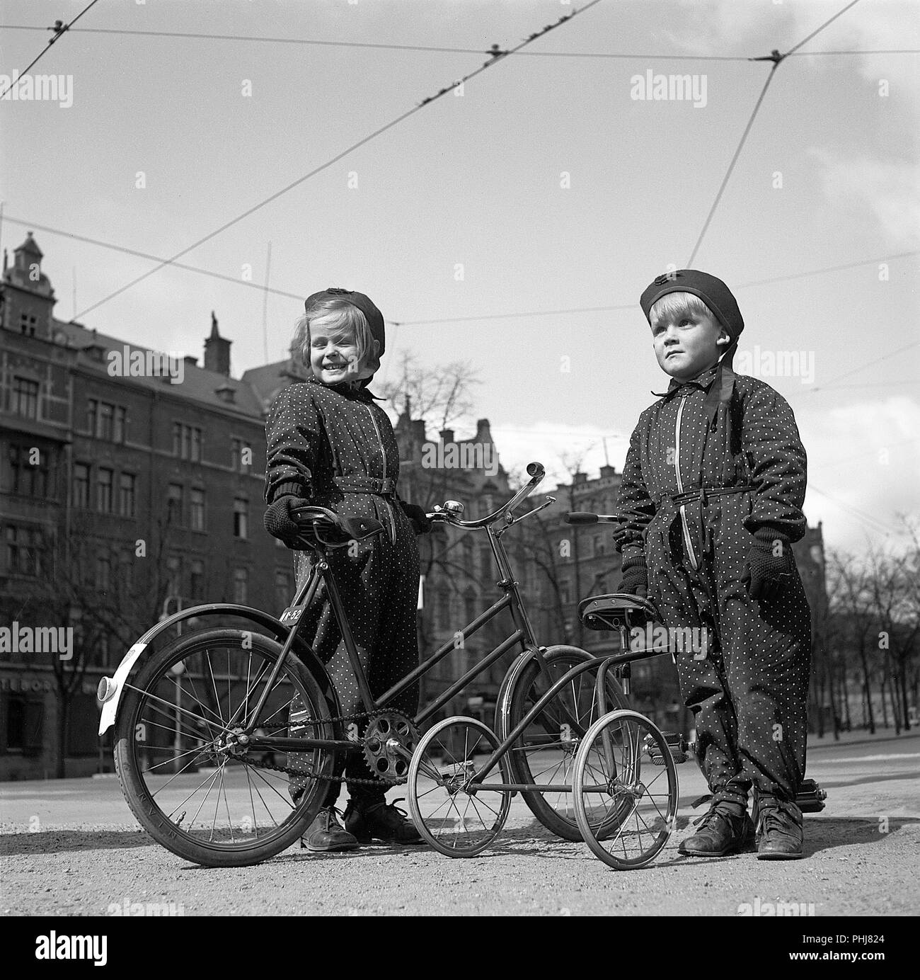 1940 enfants. Deux enfants sont à l'extérieur avec leurs bicyclettes. La fille plus âgée a une roue de vélo, deux enfants et son plus jeune frère un tricycle. Suède 1942. Kristoffersson Photo ref A89-5 Banque D'Images