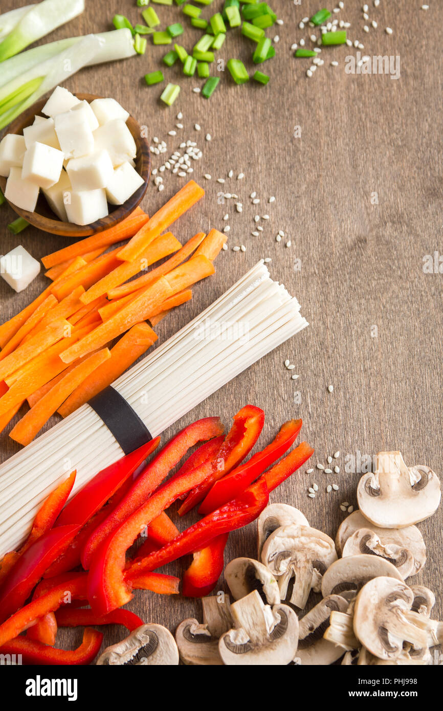 Végétalien végétarien ingrédients alimentaires asiatiques pour les sautés avec du tofu, les nouilles, les champignons et les légumes sur fond de bois avec l'exemplaire de l'espace. Banque D'Images