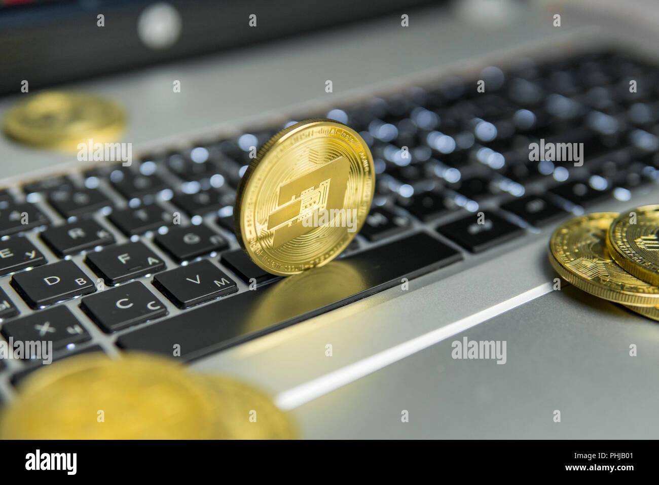 Dash d'or pièce de monnaie avec des pièces d'or traîner sur un clavier  d'ordinateur portable noir argent et diagramme graphique graphique sur un  écran en arrière-plan. L'exploitation des affaires en ligne de