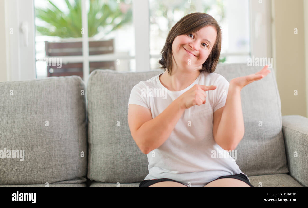 Le syndrome de femme assise sur le canapé à la maison très heureux pointant  avec la main et des doigts Photo Stock - Alamy