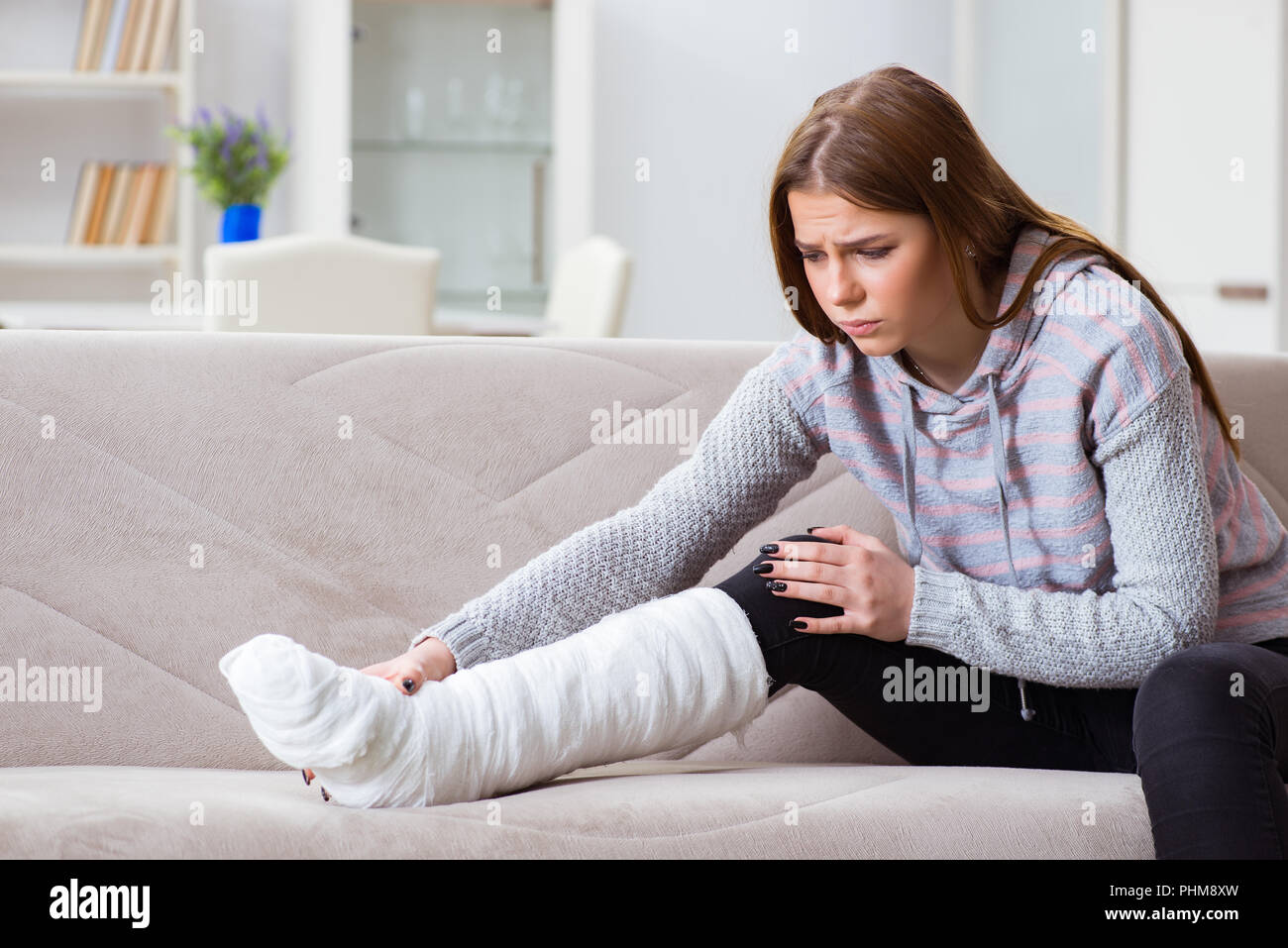 Jeune femme avec jambe cassée à la maison Banque D'Images