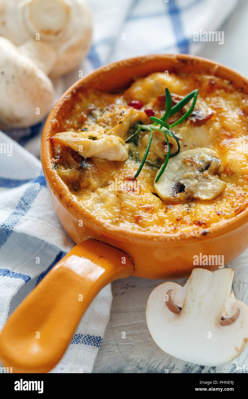 Pot en argile avec champignons sautés, poulet et fromage. Banque D'Images