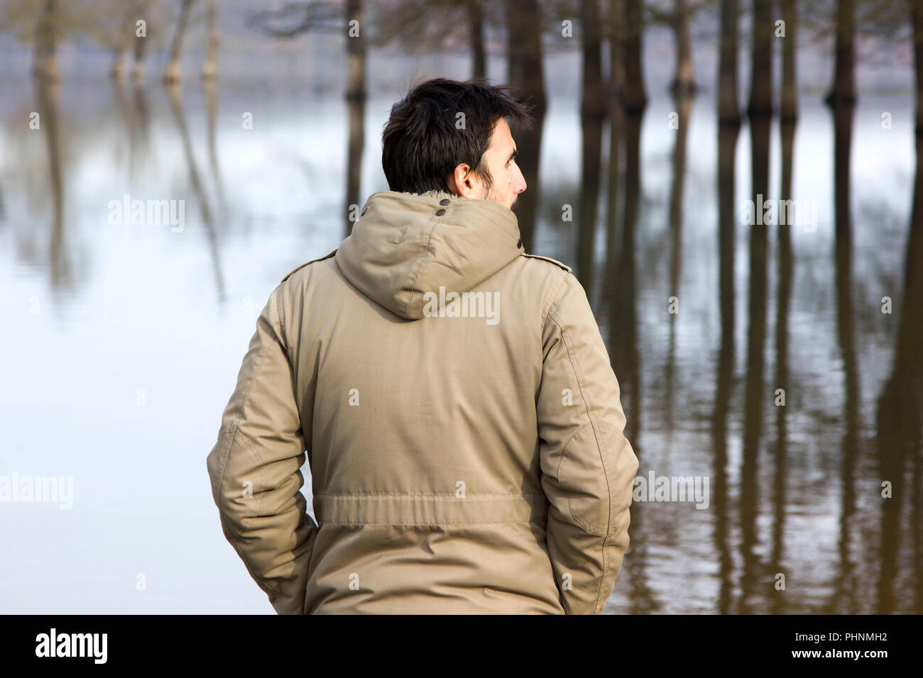 Veste homme staning à terre et l'observation d'river Banque D'Images