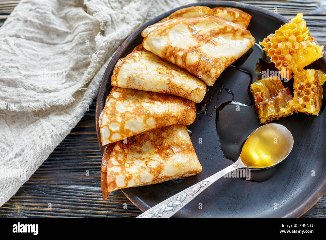 Crêpes avec du miel sur une plaque de bois. Banque D'Images