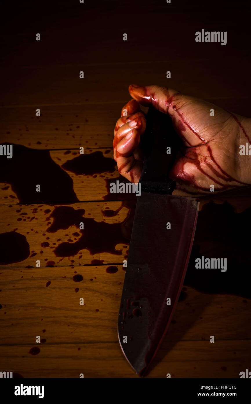 Suicide, meurtre ou de scène de crime. Main d'une personne morte imbibés de sang tenant un couteau sur le sol. Banque D'Images
