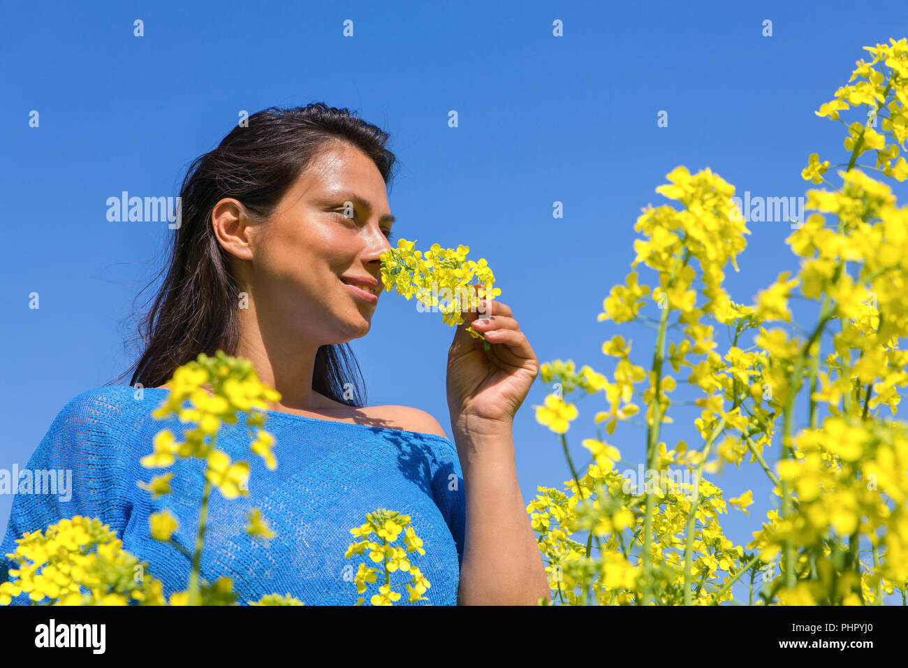 Woman smelling fleur jaune en champ de colza Banque D'Images