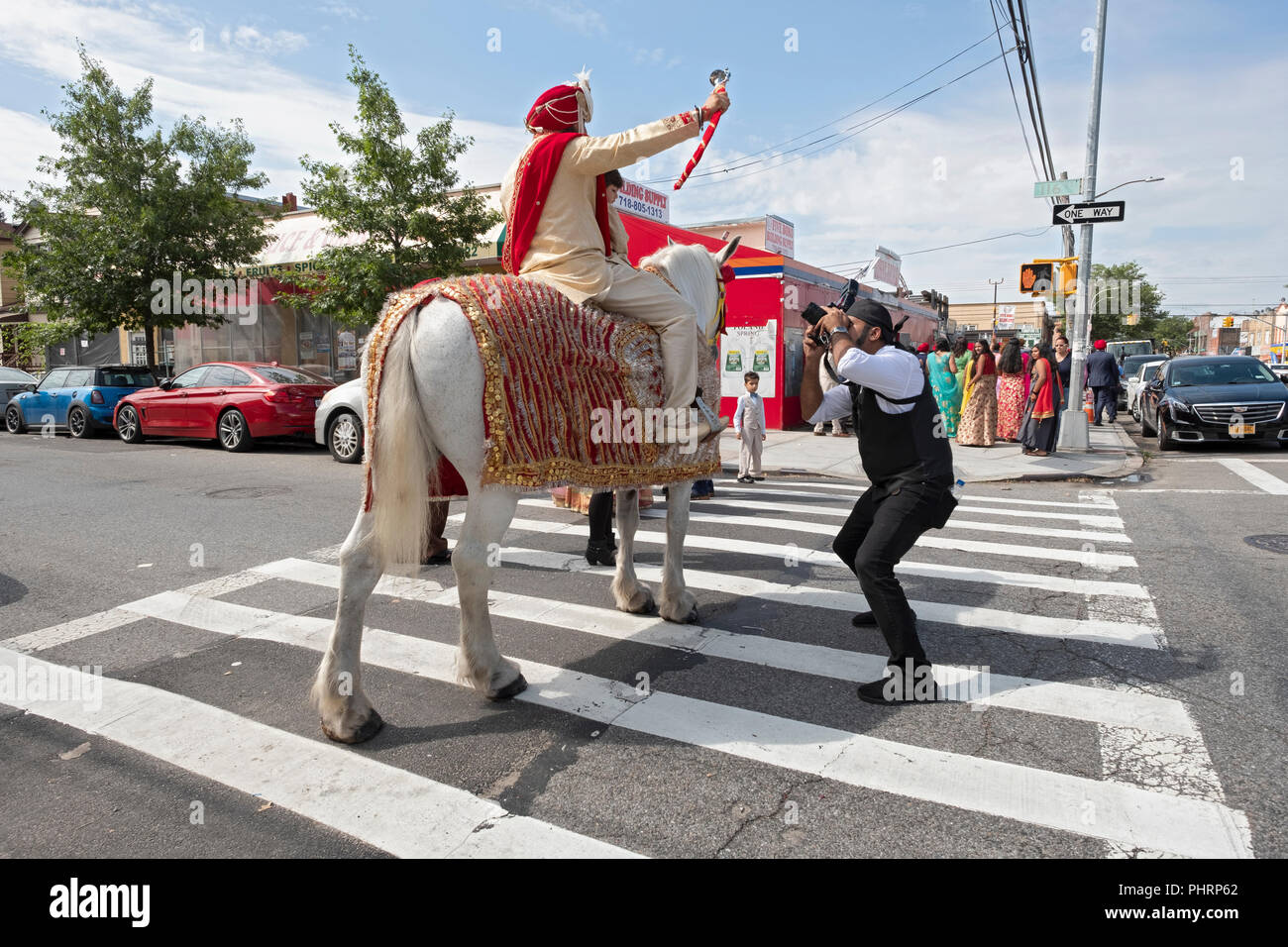 Selon la tradition, un Sikh groom sur un cheval blanc à la tête son mariage à la suite d'une procession de sa famille et amis. À Richmond Hill, Queens, NY Banque D'Images