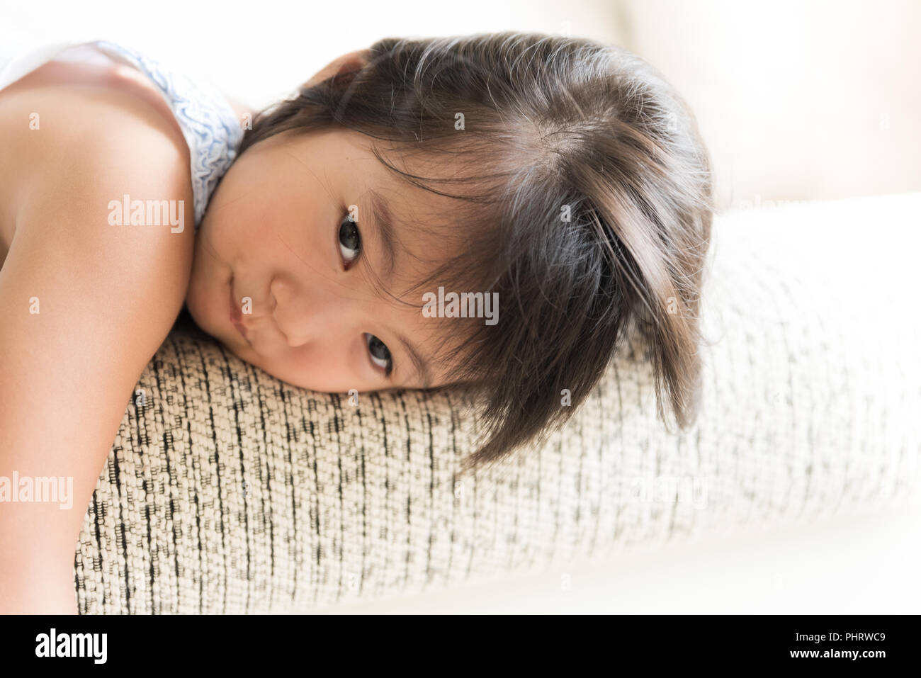 Happy cute little girl lying on sofa confortable et souriant tout en jouant à la maison. Banque D'Images