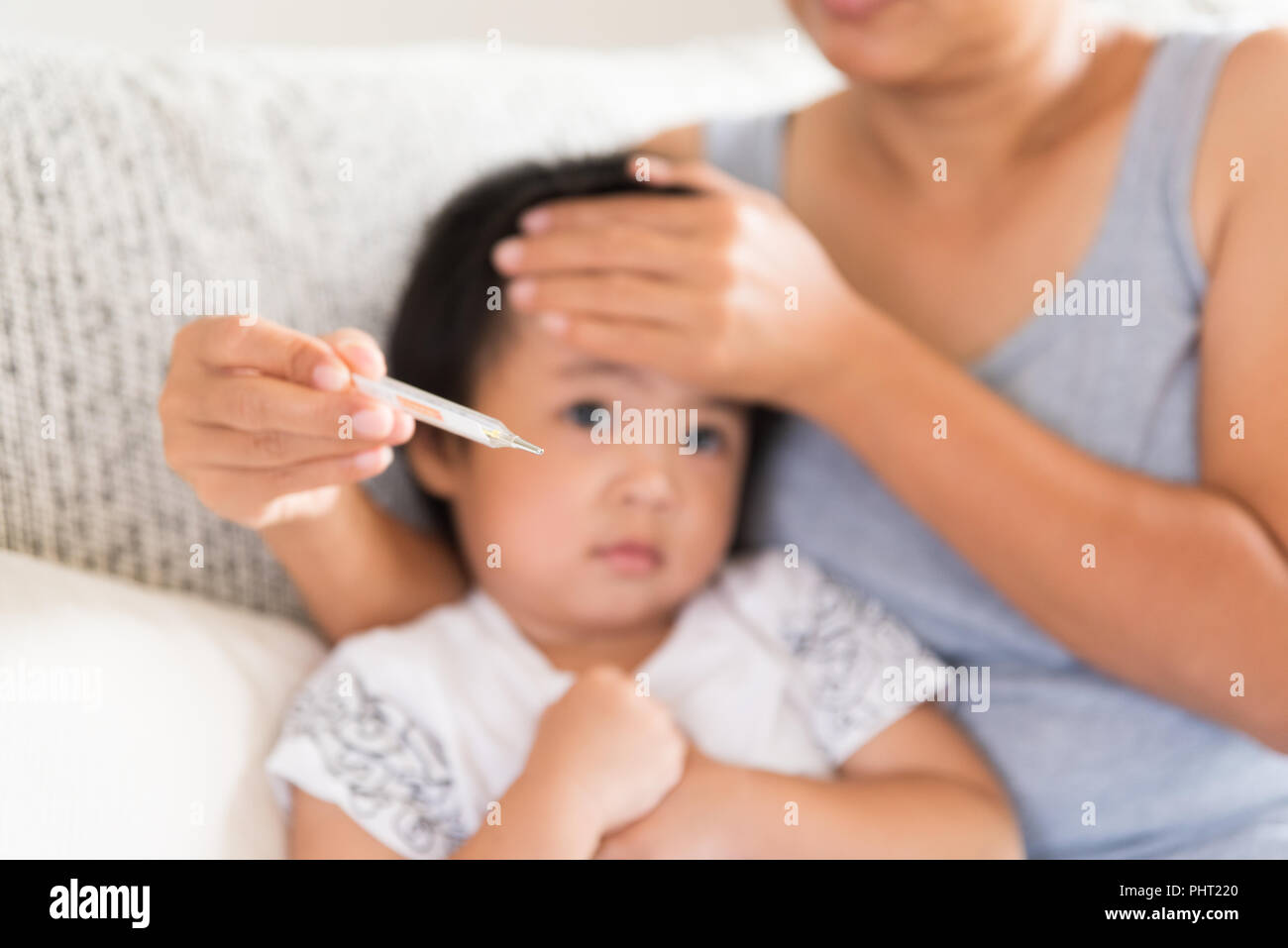 Gros Plan D Une Mere De Verifier La Temperature De Son Bebe Avec Un Thermometre Sur Un Canape Dans La Salle De Sejour A La Maison La Medecine Et Des Soins D Hiver Photo