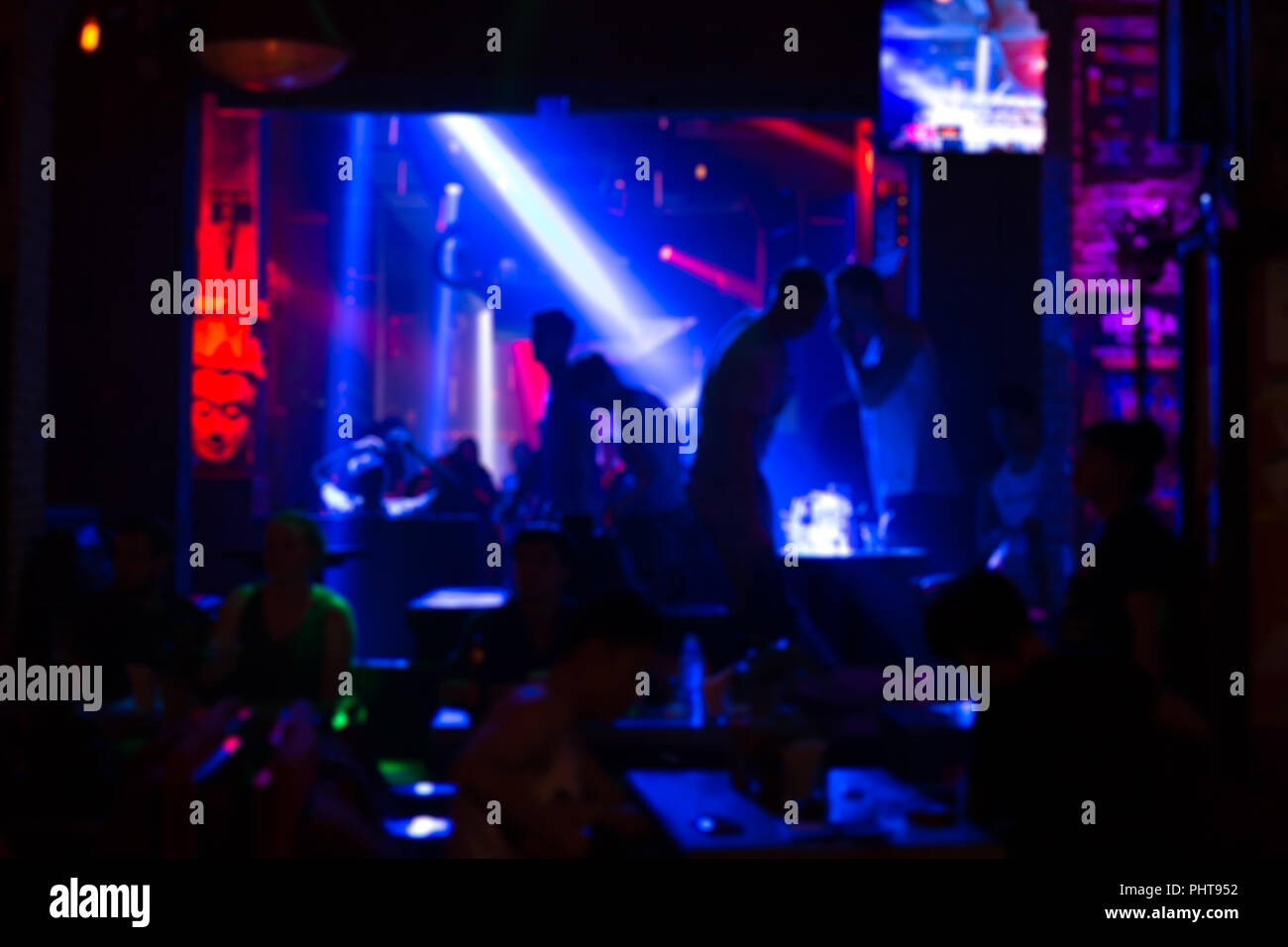 Image flou floue - les personnes à l'intérieur des lumières laser couleur disco club en arrière-plan. Banque D'Images