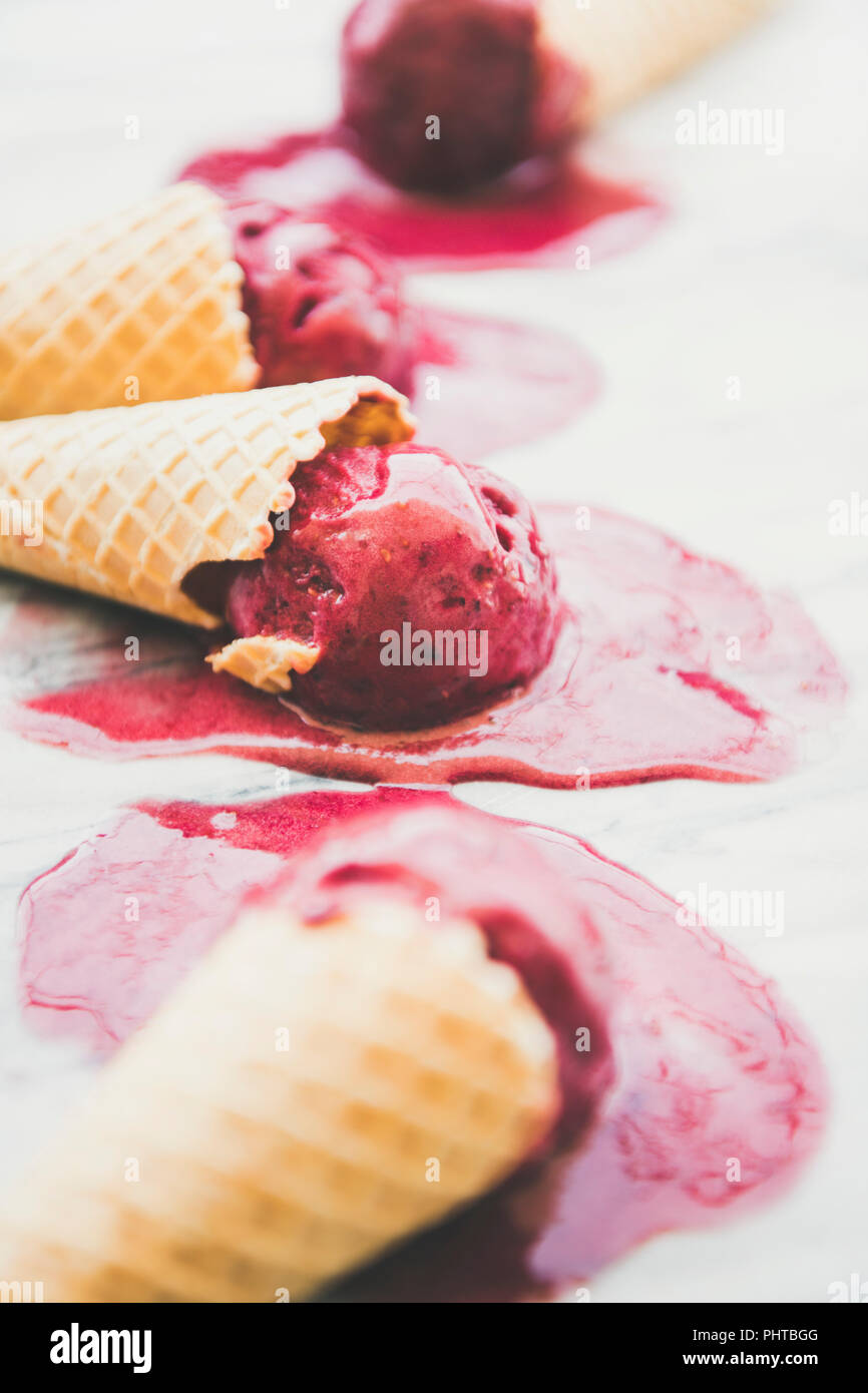 Dessert d'été frais. Naturel de fusion sorbet framboise glace boules à cônes alvéolés doux plus en arrière-plan, selective focus. S végétalien sain Banque D'Images