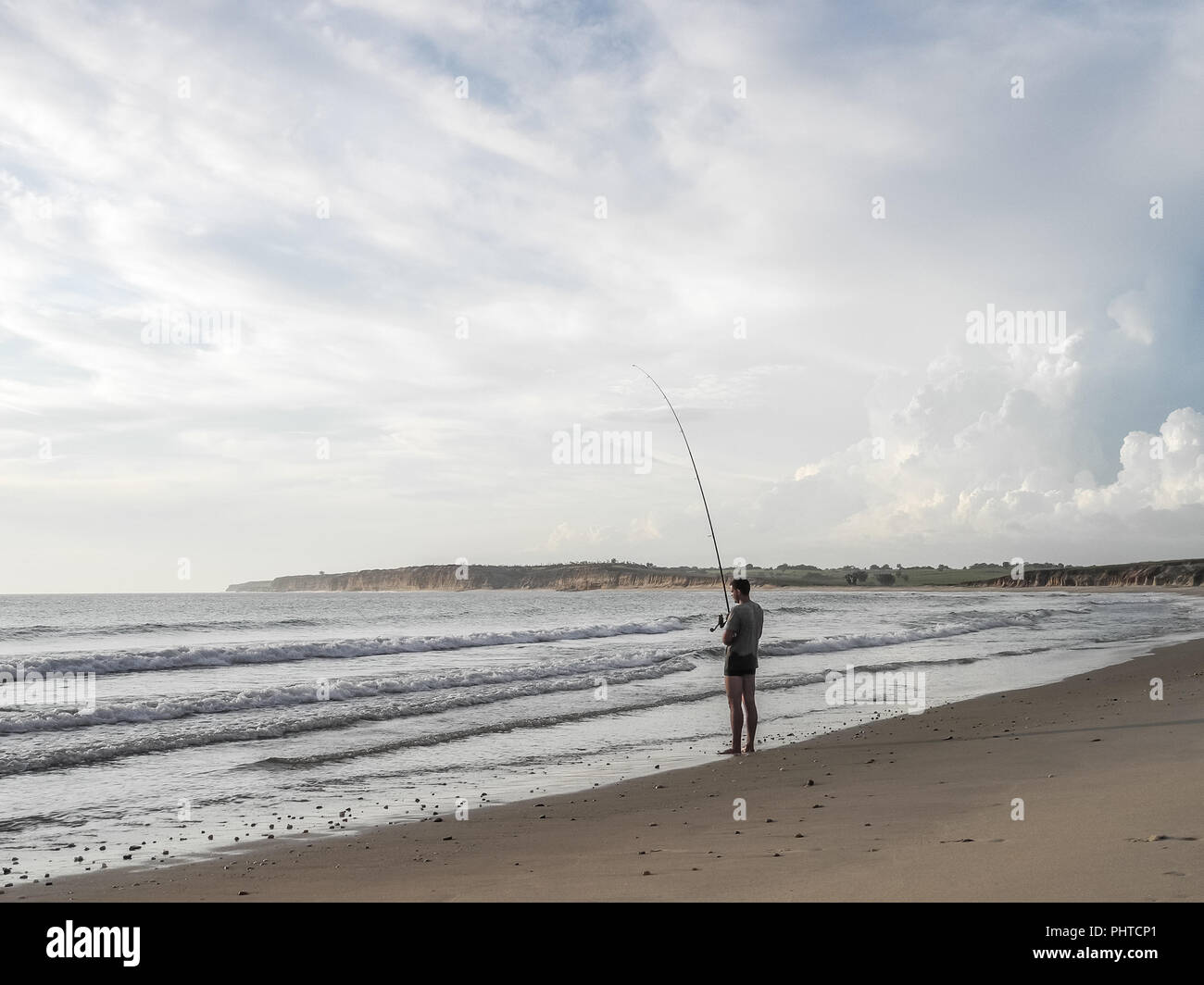 Luanda, Angola - le 26 avril 2014 Loisirs : jeune pêcheur debout à Beach au nord de Luanda, Angola, la pêche à la ligne de l'Afrique. Banque D'Images