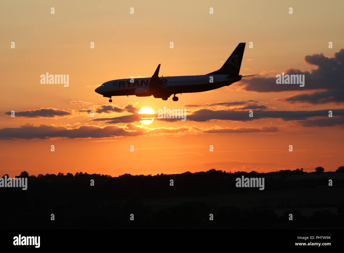 Un Boeing 737 de Ryanair EI-ESW vole en face du soleil couchant car il rend son approche finale sur l'aéroport d'Édimbourg Banque D'Images