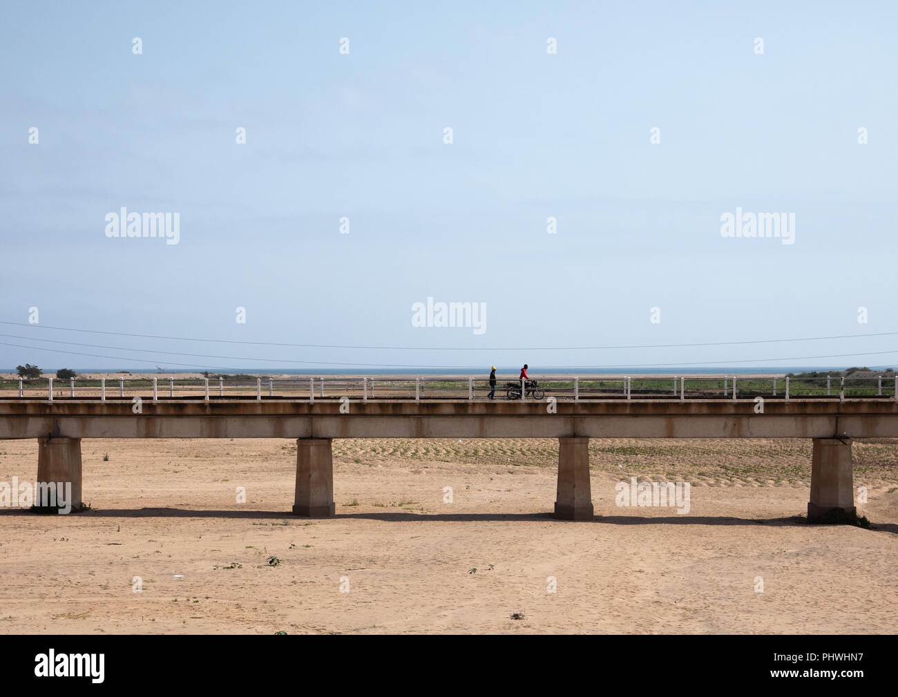 Les hommes de l'Angola pour traverser un pont sur une rivière à sec, la province de Namibe, Namibe, Angola Banque D'Images