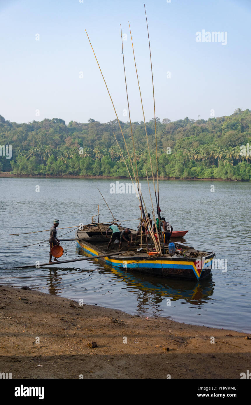 Ouvriers portant le sable extrait du bateau à la rive près de Volvoi, Goa, Inde Banque D'Images