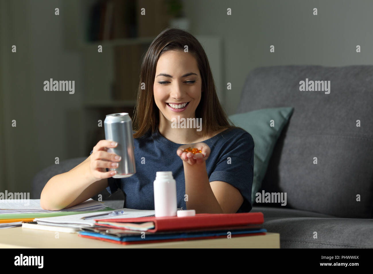 Happy student avec energy drink et supplément vitaminique comprimés à la maison Banque D'Images