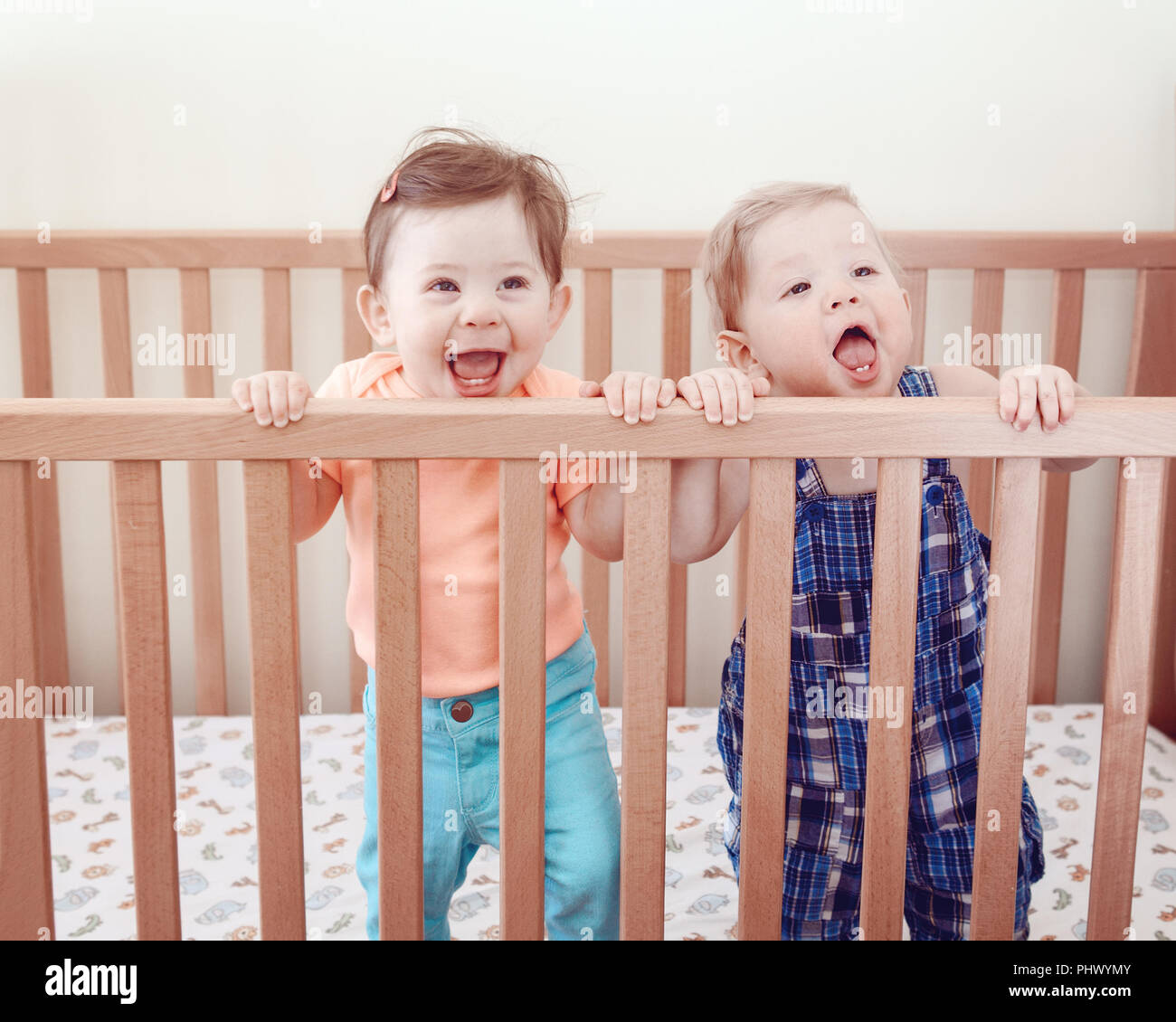 Portrait de deux adorables bébés mignon drôle frères et sœurs les amis de neuf mois au lit permanent lit-bébé rire, sourire à la caméra en route, style ev Banque D'Images