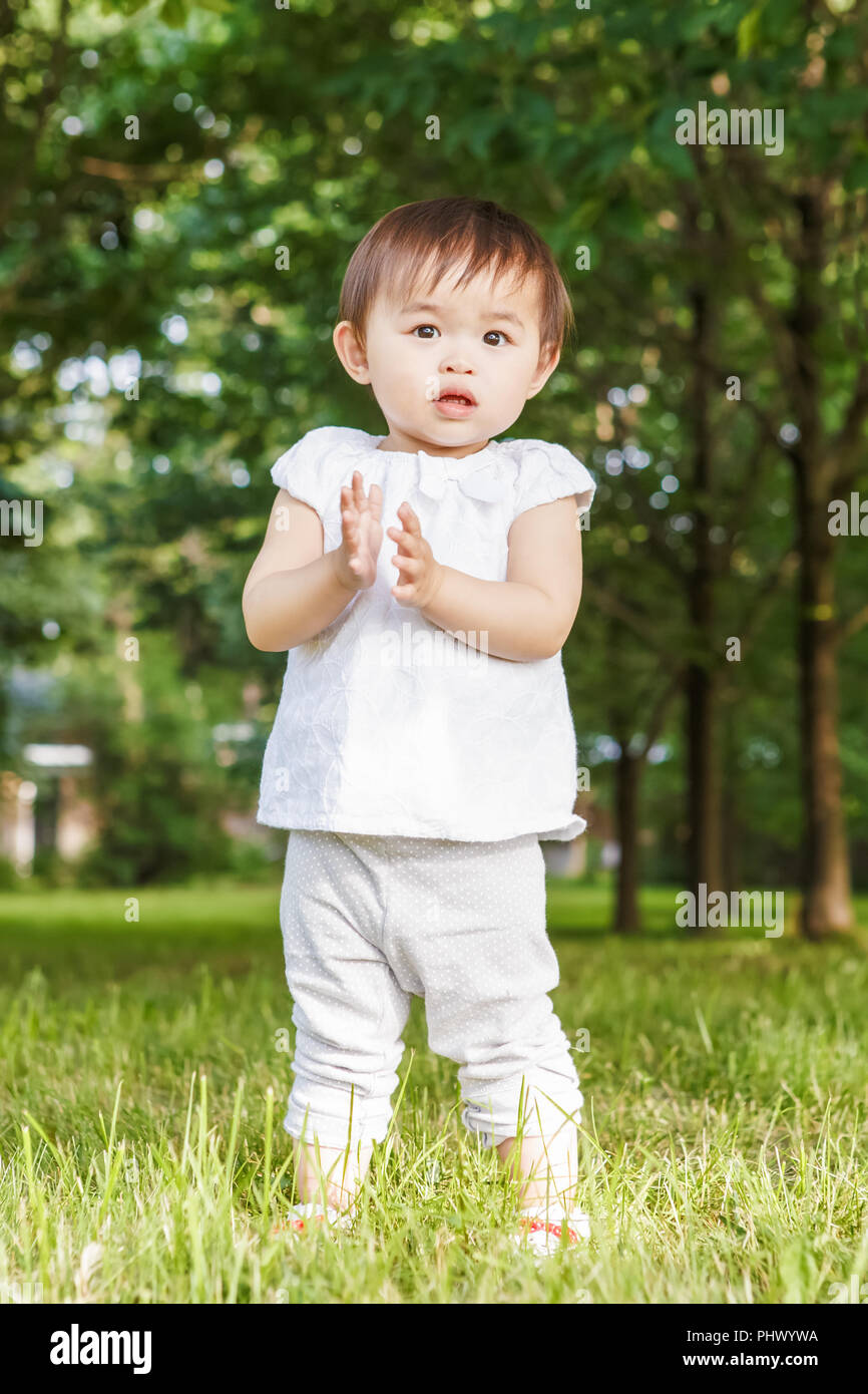 Portrait Of Cute Adorable Petite Fille Asiatique Enfants Bebe D Un An Dans Un Pantalon Blanc Shirt Debout Sur L Herbe Pres De Champ Sur Le Coucher Du Soleil Jouant Des Mains Il Photo Portrait Of Cute Adorable Petite Fille Asiatique Enfants Bebe D Un An Dans Un Pantalon Blanc Shirt Debout Sur L Herbe Pres De Champ Sur Le Coucher Du Soleil Jouant Des Mains Il Photo