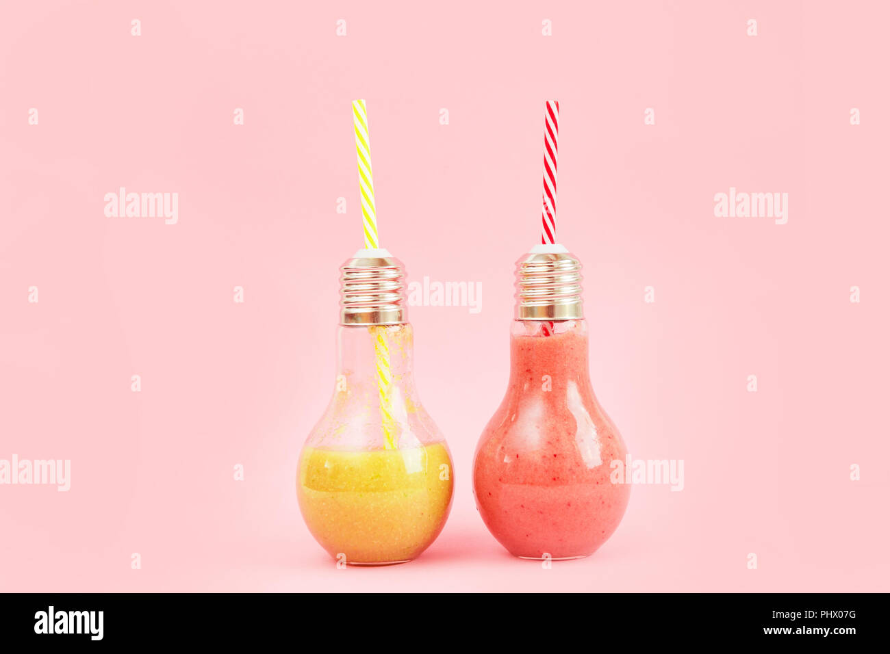 Deux pots en forme de lampe avec smoothies aux fruits isolé sur fond rose. Banque D'Images