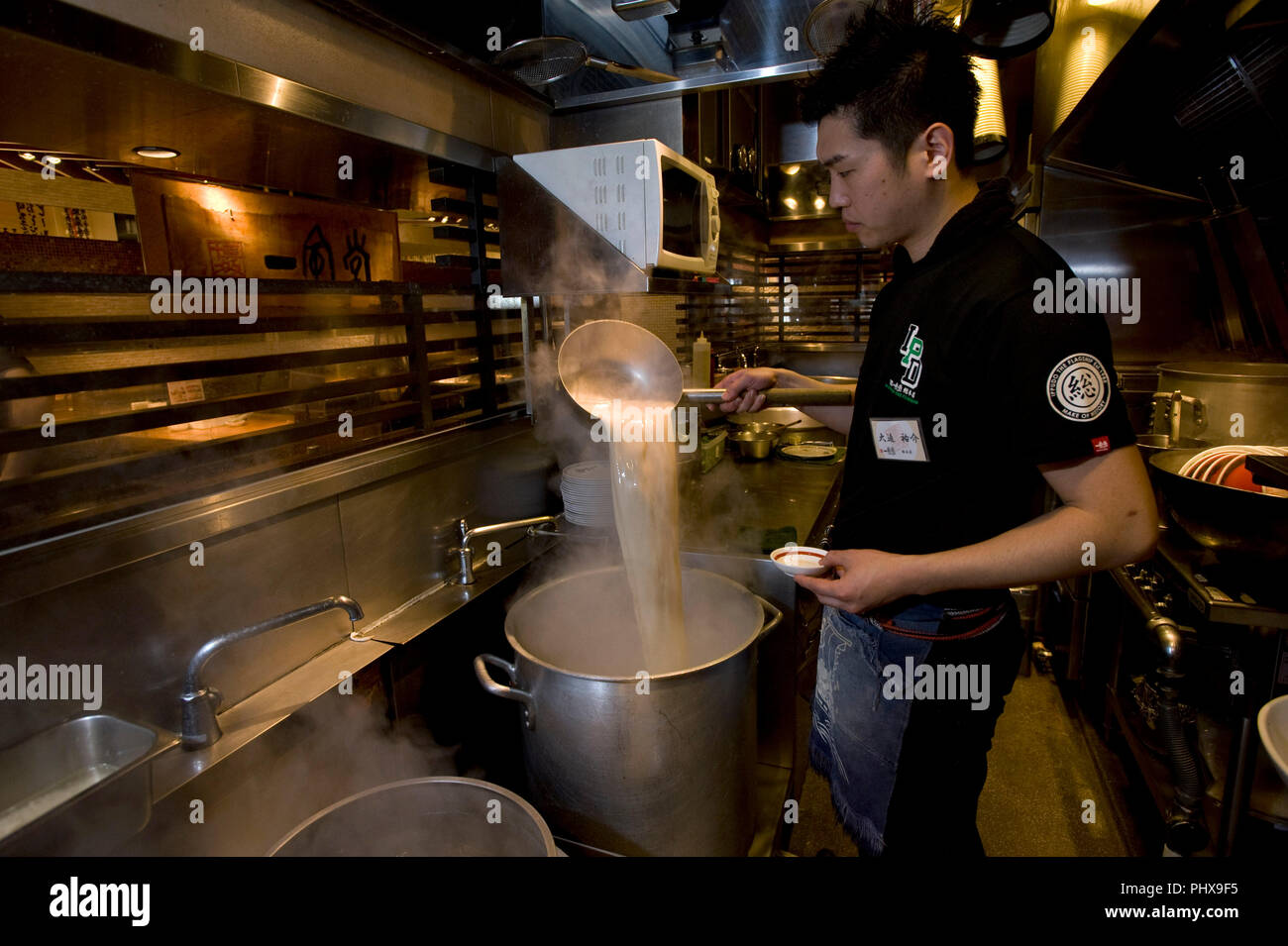 Store Manager Yusuke Osako prépare la soupe dans la cuisine à Hakata Ramen Ippudo dans le magasin principal du daimyo du district de la ville de Fukuoka, Fukuoka Prefe Banque D'Images