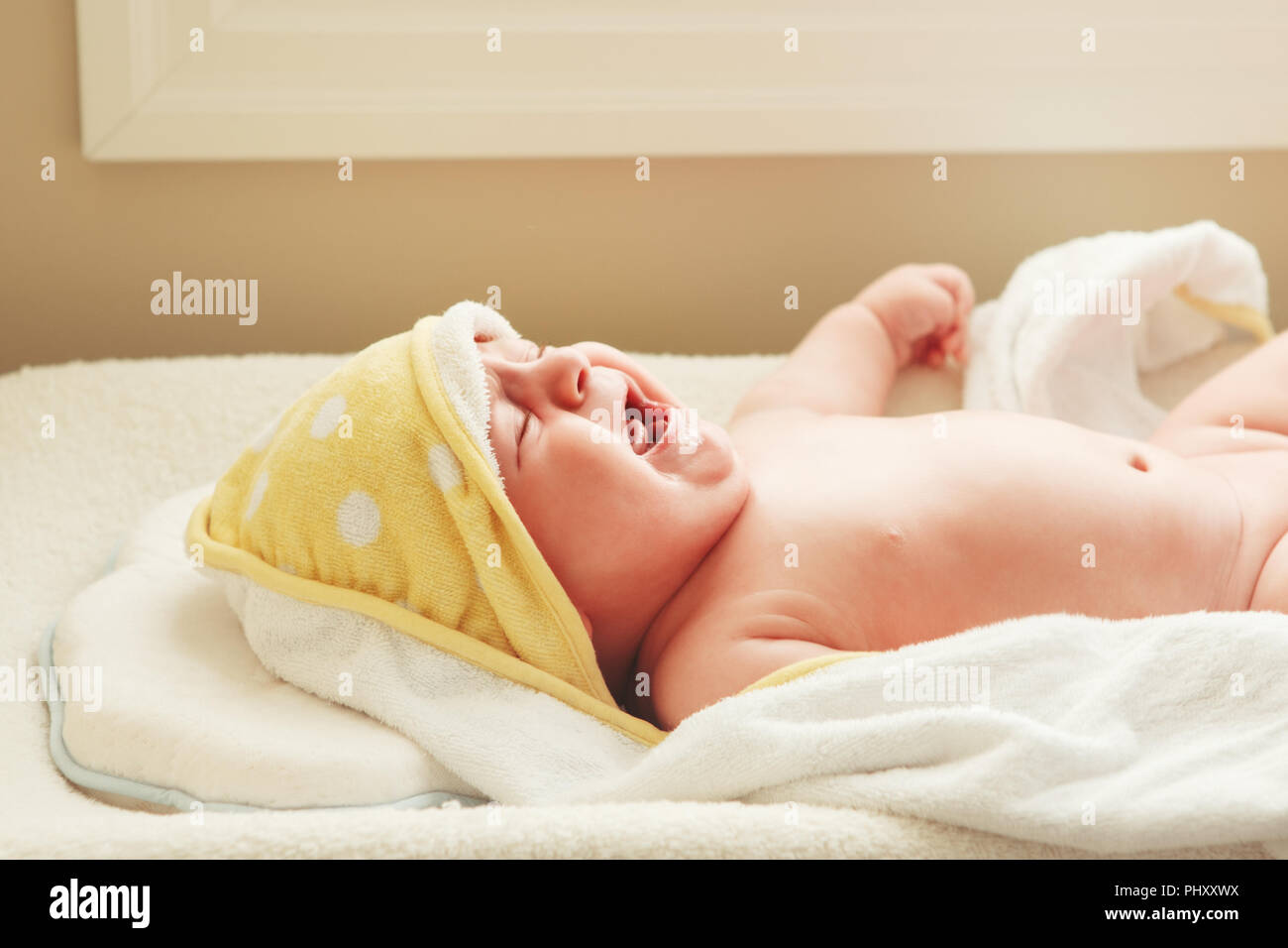 Closeup portrait de pleurer crier bébé nouveau-né enfant allongé sur une table  à langer, couverts enveloppé dans une serviette de bain après avoir pris,  le mode de vie de réelles émotions c