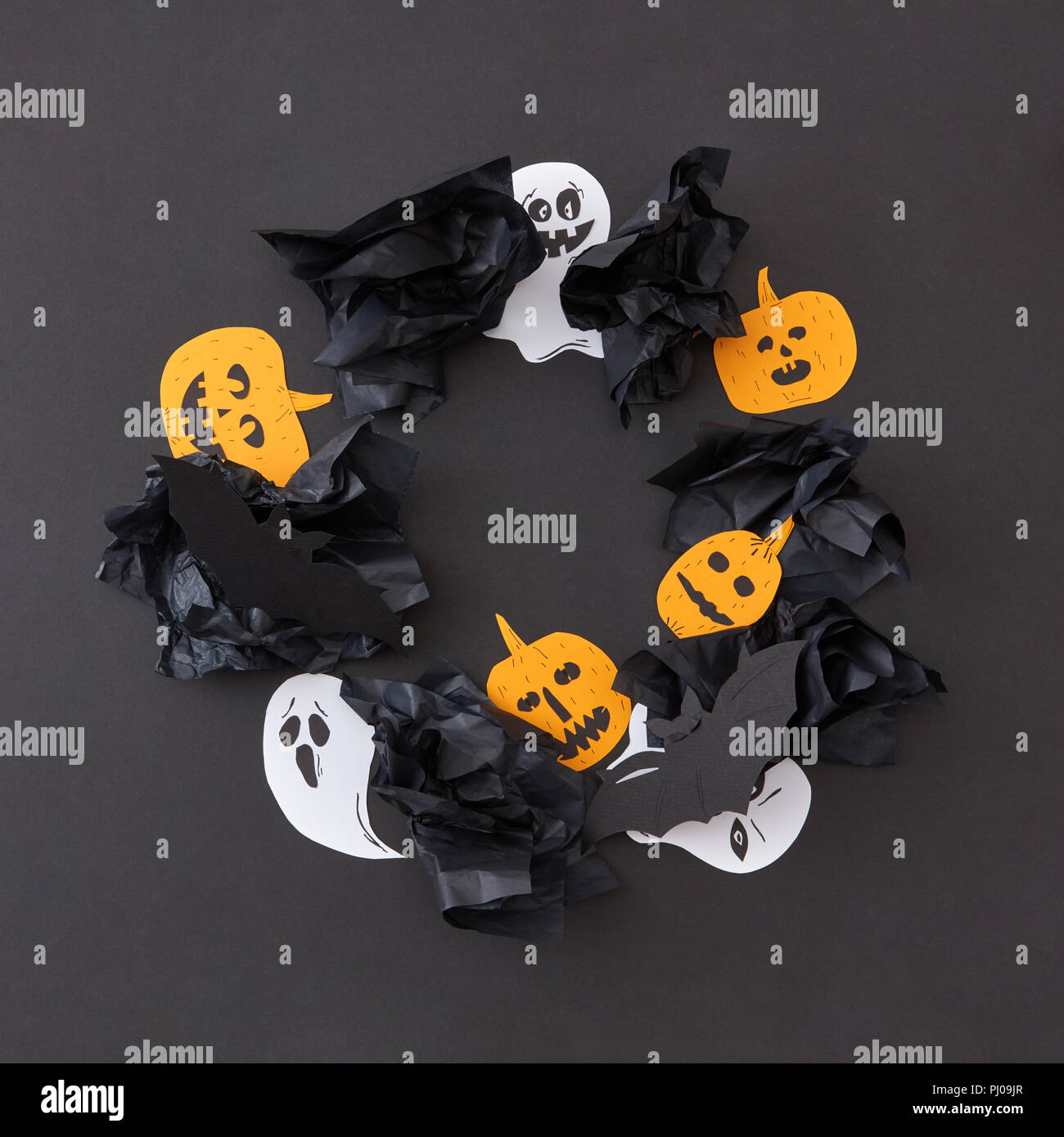 Cadre décoratif de round battant blanc flottant esprit fantômes et citrouilles jaune souriant, chauves-souris noire sur un fond de papier noir. Banque D'Images