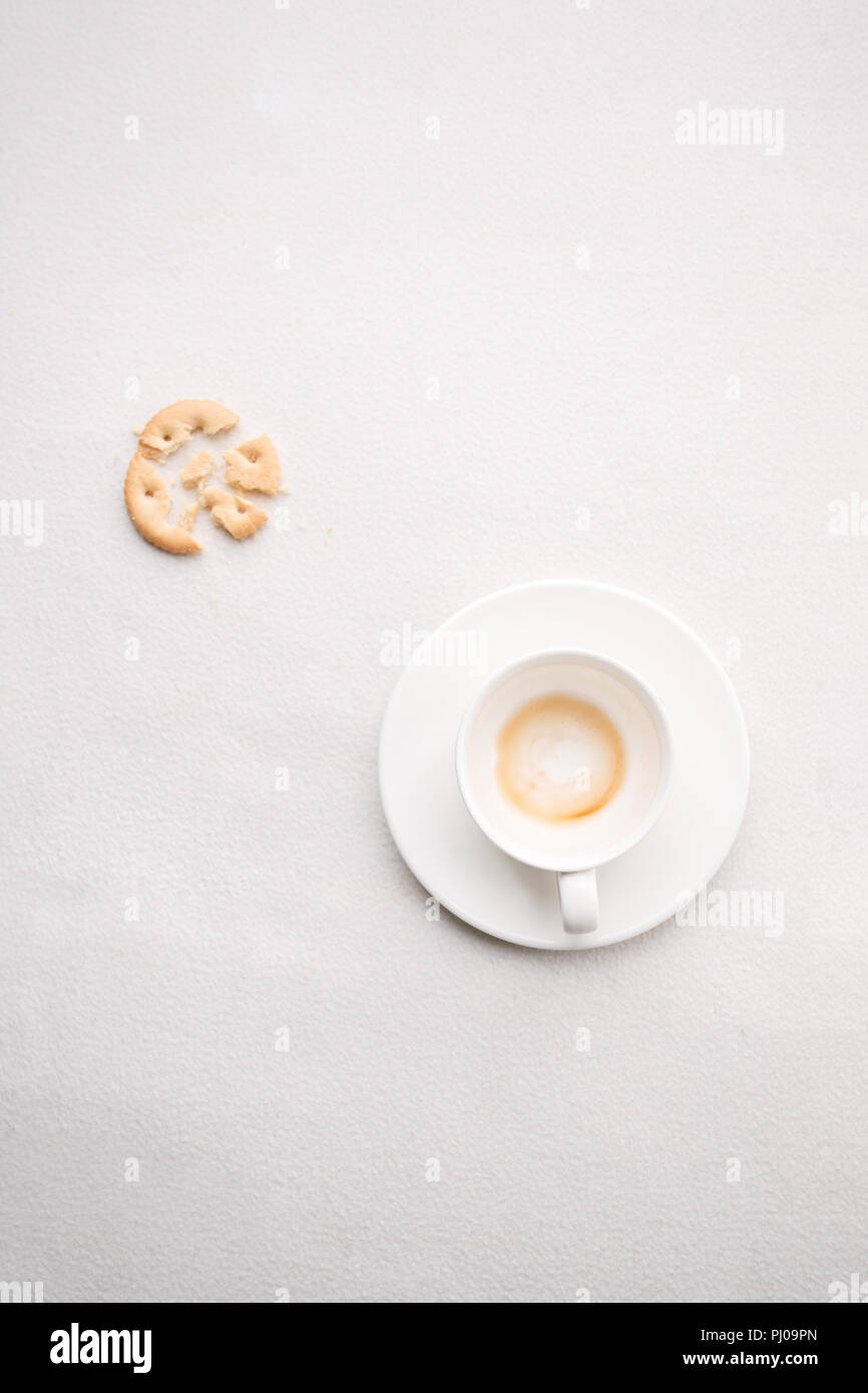 La tasse de café vide après boire et croustillant snack sur fond blanc, à la mode, concept monochrome minime matin endormi paresseux closeup Banque D'Images