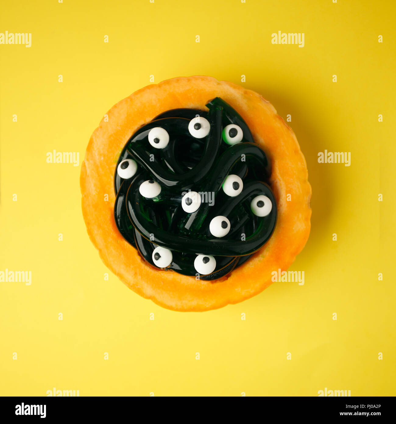 Jelly worms avec les yeux sur l'Halloween dans plaque orange citrouille. Halloween de gros plan alimentaire Banque D'Images