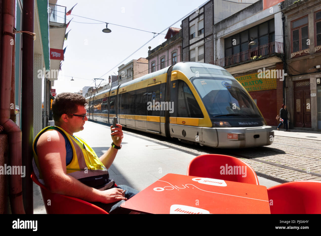 Por176 portugal, Porto, Coimbra, Rua de Brita Capelo, suburban light rail train passing café de la chaussée Banque D'Images