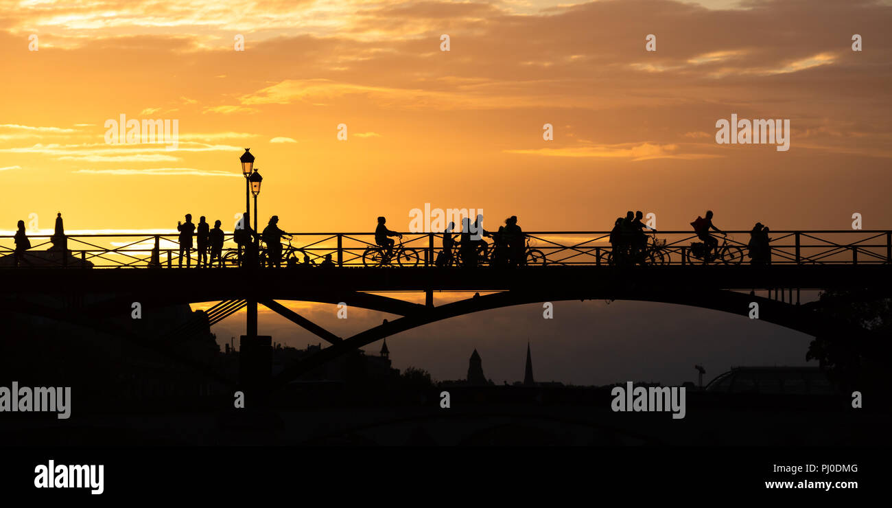 La silhouette de gens qui traversent un pont au coucher du soleil à Paris Banque D'Images