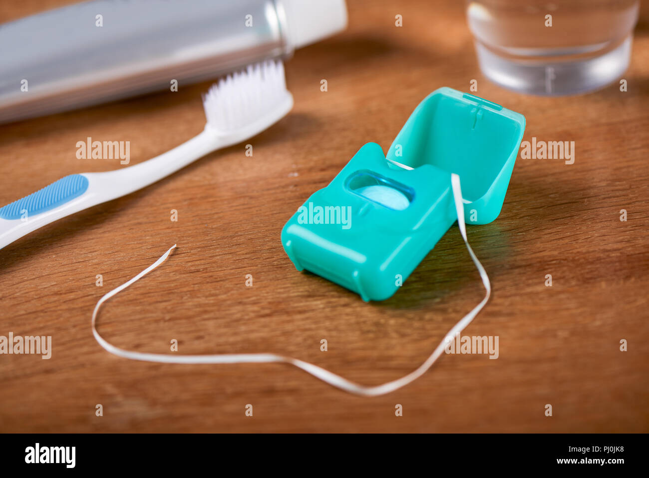 Fil dentaire avec couvercle ouvert sur un fond de brosse à dents et dentifrice Banque D'Images